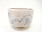 Front view of the Shigezo Sato Benishino chawan showing its milky ivory glaze, softly irregular rim, and misty blue-gray brushwork.