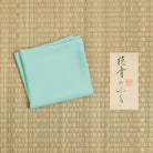 Shinbashi mint green silk fukusa displayed on tatami mat for traditional Japanese tea ceremony practice.