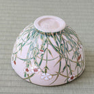 Underside view of the Shisen Asano Nadeshiko chawan showing the raised ceramic foot and dense green grass and floral decoration around the exterior