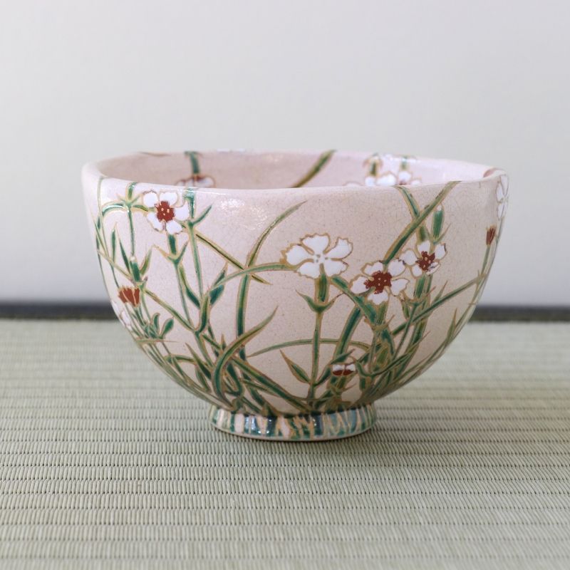 Pre-owned matcha bowl by Shisen Asano featuring a delicate Nadeshiko Japanese pink motif with white and deep red flowers and flowing green grasses on a soft pale pink glaze