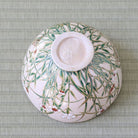 Bottom view of the Shisen Asano Nadeshiko matcha bowl showing its circular foot and floral decoration continuing across the pale pink exterior