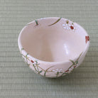 Top interior view of the Shisen Asano Nadeshiko matcha bowl showing its soft pale pink glaze and hand-decorated floral and grass motif around the rim