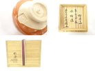 Collage showing the pale foot and underside of the Shoraku Sasaki Red Raku bowl together with its box inscription and packaging.