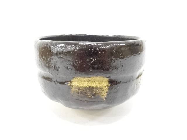 Side view of the Shoraku Sasaki Sennen no Midori Black Raku chawan showing its deep glossy black glaze, irregular hand-formed shape, and gold-toned accent
