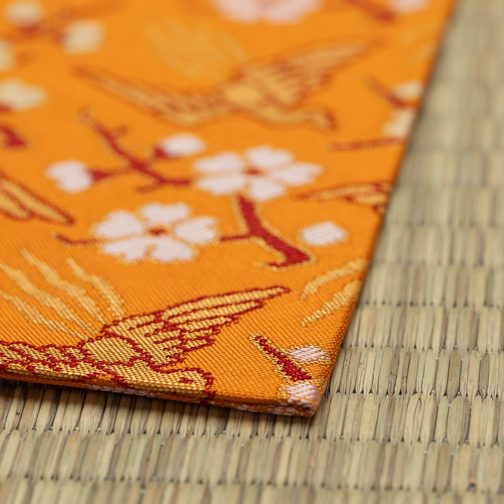 Close-up of the Nishijin silk weave and vibrant orange fabric of Shoukougire Kobukusa.