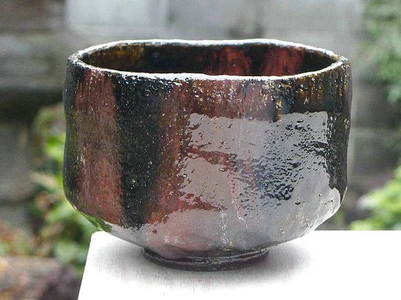 Right-side view of the Shuraku Kiln Black Raku bowl showing glossy black glaze and a broad copper-red surface variation.