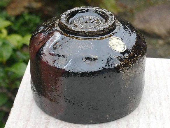 Underside view of the Shuraku Kiln Black Raku matcha bowl showing its circular foot and glossy hand-formed base.