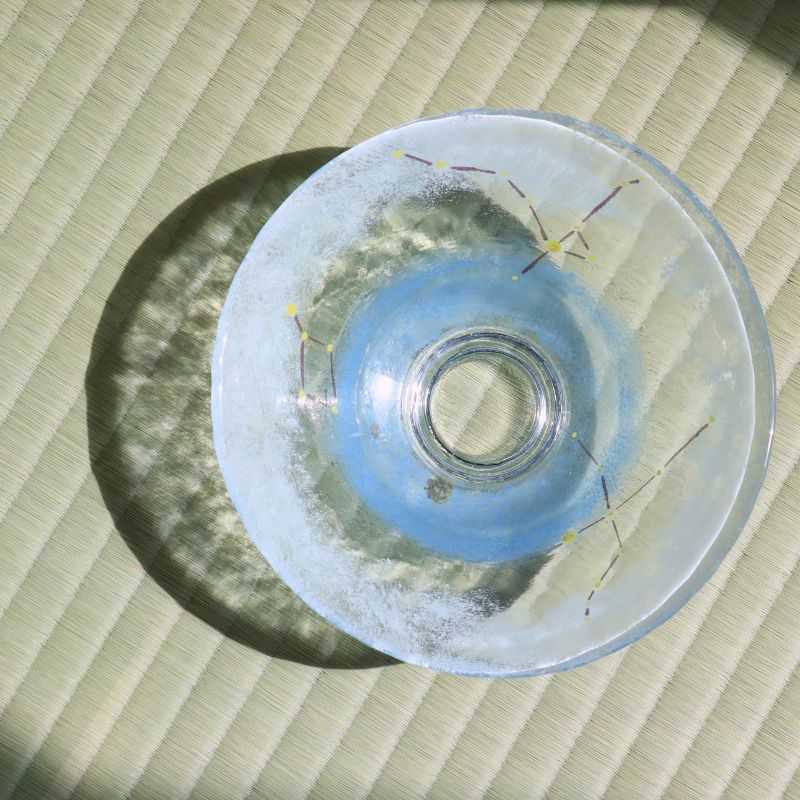 Close overhead view of the transparent glass foot and constellation decoration casting a soft circular shadow on tatami.