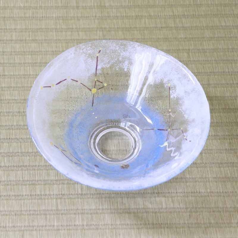 Top view of a handcrafted pale blue glass hirachawan decorated with shimmering stars and colored summer constellation lines on tatami.