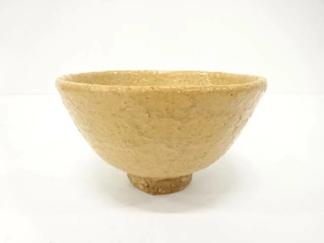 Front view of the Takashi Ajishita Hagi chawan showing its gently flared form, irregular rim, and warm golden-beige speckled glaze.