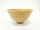 Front view of the Takashi Ajishita Hagi chawan showing its gently flared form, irregular rim, and warm golden-beige speckled glaze.