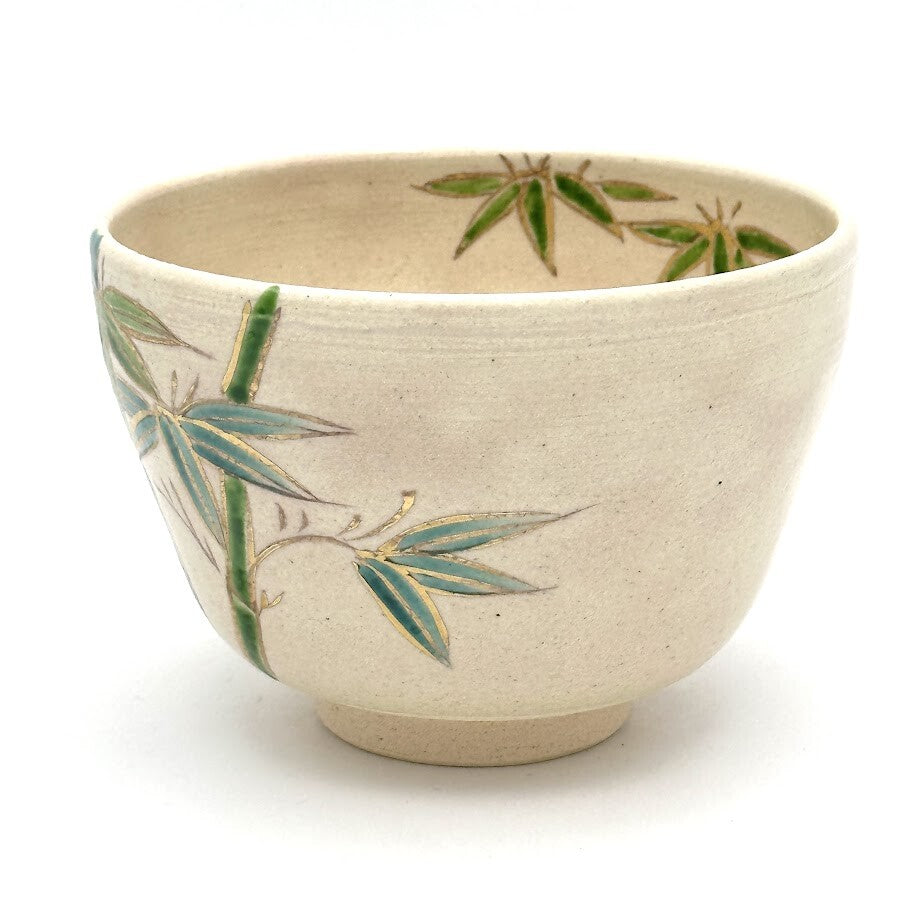 Angled view of the hand-painted Take bamboo Kyo Ware chawan showing bamboo leaves, blue-green stalks, and gold rim detail