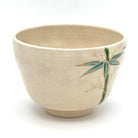Side view of the Kyo Ware matcha bowl highlighting hand-painted bamboo in green and blue on the warm beige glaze