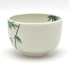 Angled view of the Take Suzume Kyo Ware chawan highlighting the hand-painted bamboo motif and ivory glazed form