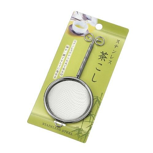Stainless steel tea strainer on a green packaging background