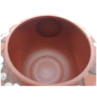 Close-up of a terracotta pot with a perforated bottom on a white background