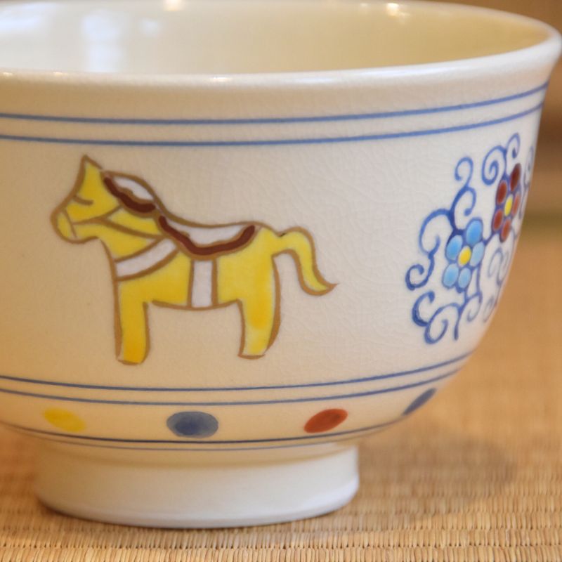 Close-up of a yellow hand-painted horse on the ivory exterior of the Kyo Ware matcha bowl.