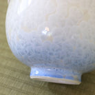 Close-up of the Tōan katakuchi bowl showing the blue glazed foot and the transition from pale blue to white Hana-Kesshō flower crystal glaze