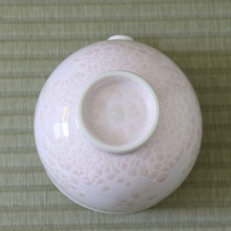 Underside view of the Tōan Hana-Kesshō cherry blossom pink katakuchi bowl showing its circular ceramic foot and pale crystalline glaze across the base