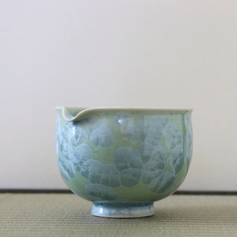 Side view of the Tōan Hana-Kesshō green katakuchi bowl showing its rounded form, pouring spout, and layered flower crystal glaze