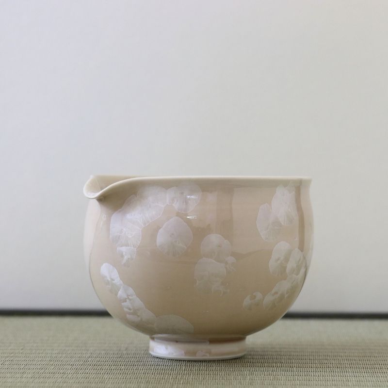 Side view of the Tōan Hana-Kesshō natural beige katakuchi bowl showing its rounded form, pouring spout, and delicate ivory flower crystal glaze patterns