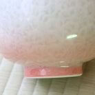 Close-up of the Tōan katakuchi bowl showing the transition from white flower crystal glaze to soft pink near the ceramic foot