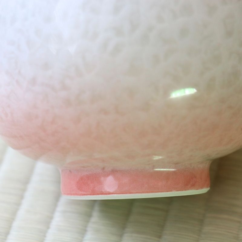 Close-up of the Tōan katakuchi bowl showing the transition from white flower crystal glaze to soft pink near the ceramic foot