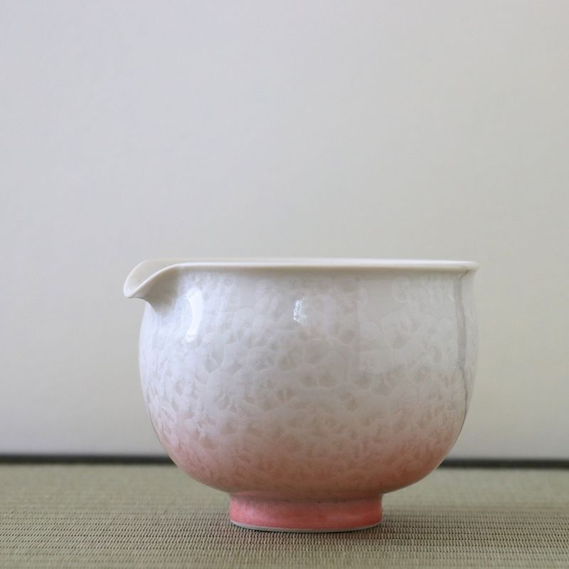 Side view of the Tōan Hana-Kesshō katakuchi bowl showing its pouring spout, rounded form, and soft pink to white crystalline glaze
