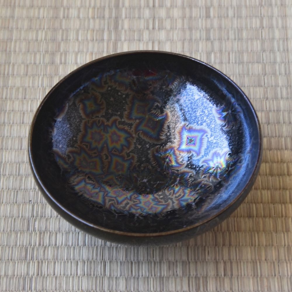 Top interior view of the Touan Hoshi-Kessho flat matcha bowl showing radiant star-like crystal patterns across the glossy black glaze