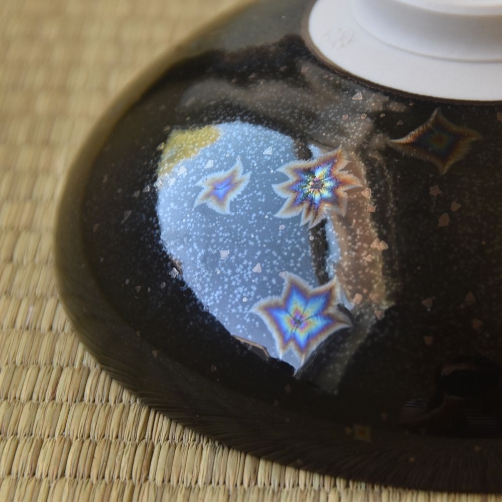 Close-up underside detail of the Touan matcha bowl highlighting colorful star-like Hoshi-Kessho crystal formations in the glossy black glaze