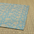 Folded edge of the hand-sewn dashibukusa showing its turquoise ground and continuous gold-toned vine pattern.