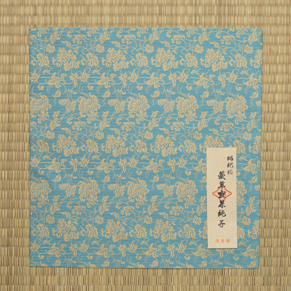 Turquoise-blue silk dashibukusa displayed with its Japanese maker label and product information card.