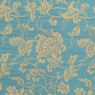 Close-up of scrolling vines and stylized floral motifs woven in gold-toned silk on a turquoise-blue ground.