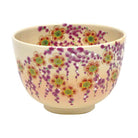 Studio view of the hand-painted Kyo Ware matcha bowl with abundant weeping cherry blossoms, green leaves, and gold floral details.
