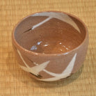 Angled top view of the Dancing Cranes matcha bowl showing its glossy brown interior and white crane decoration crossing the rim.