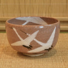 Front view of a Zouho Kiln Mino Ware matcha bowl decorated with dancing white cranes on a speckled warm brown glaze.