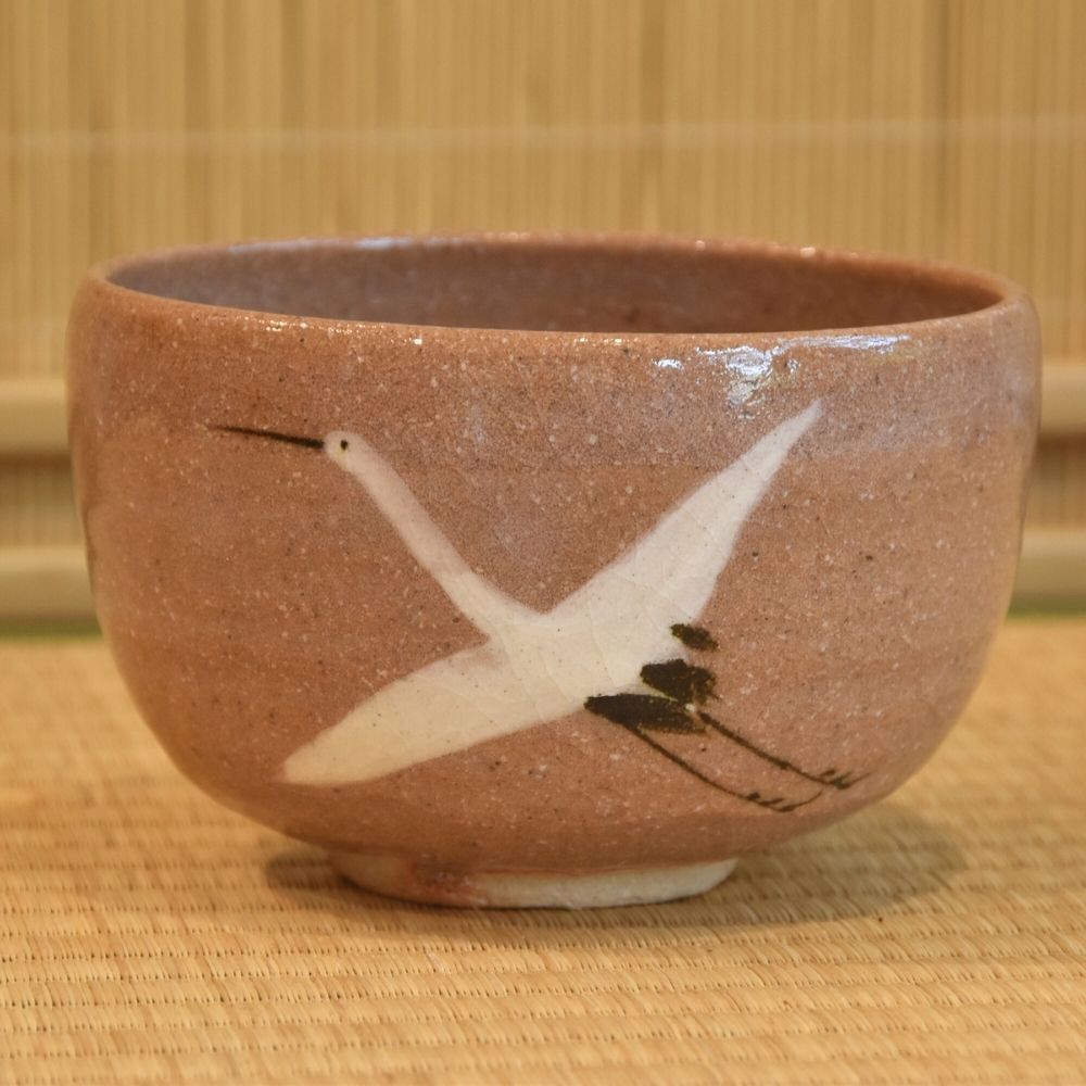 Side view of the hand-painted Mino Ware matcha bowl showing two white cranes with black and rust-colored brushwork.